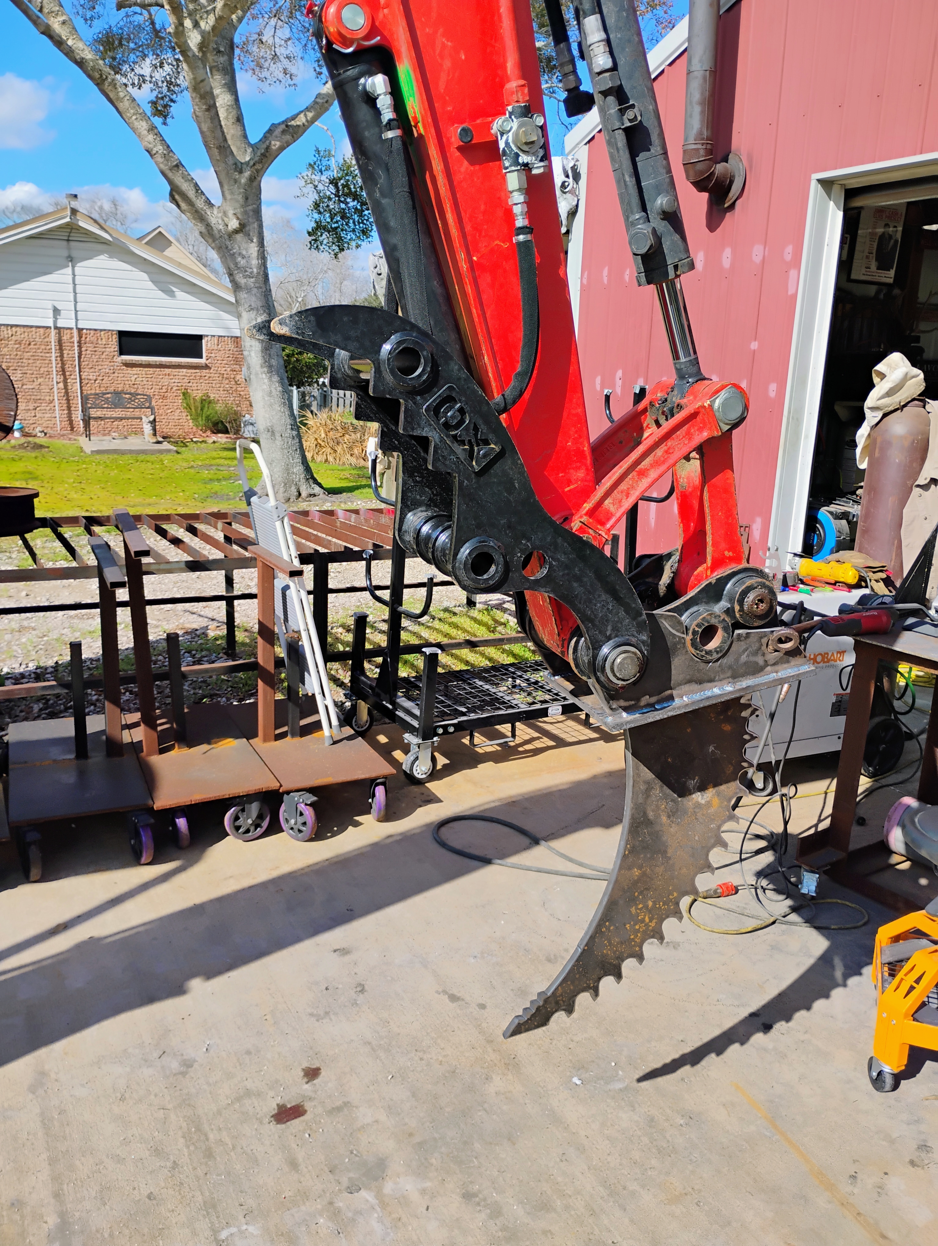 Side profile of custom ripper attachment connected to mini excavator arm