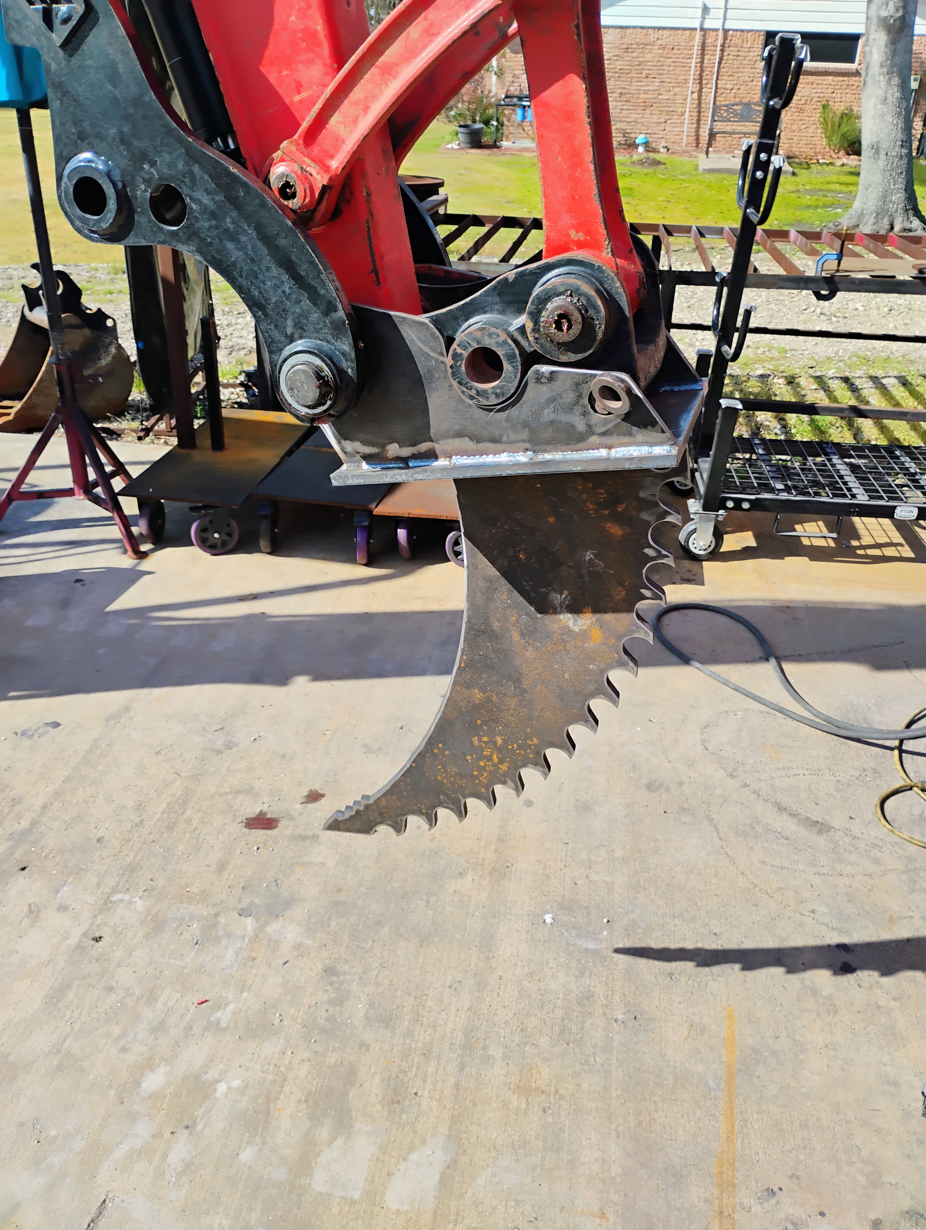 Closeup of custom ripper tooth attachment mounted to a mini excavator coupler
