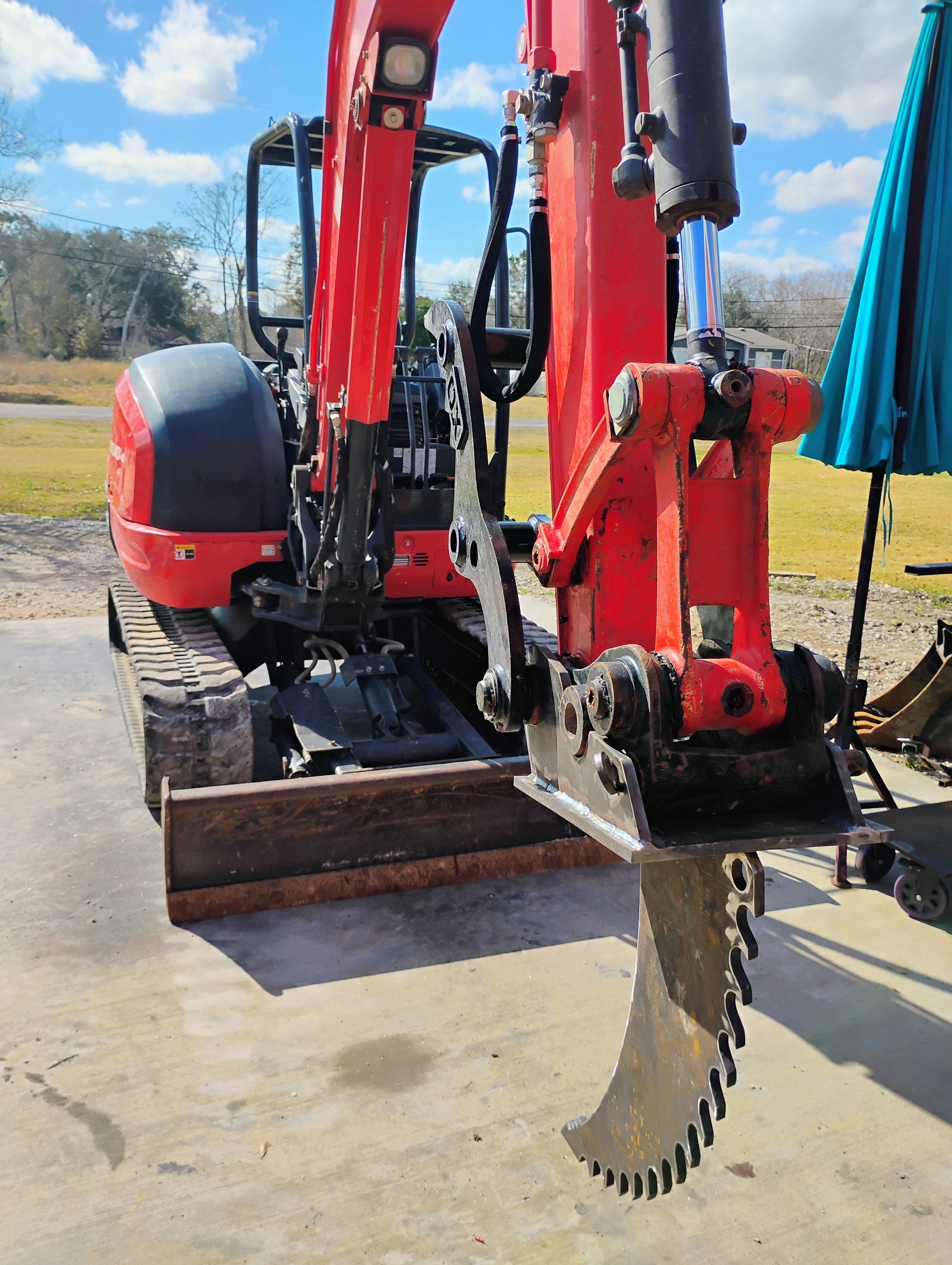 Custom ripper tooth attachment installed on a red mini excavator